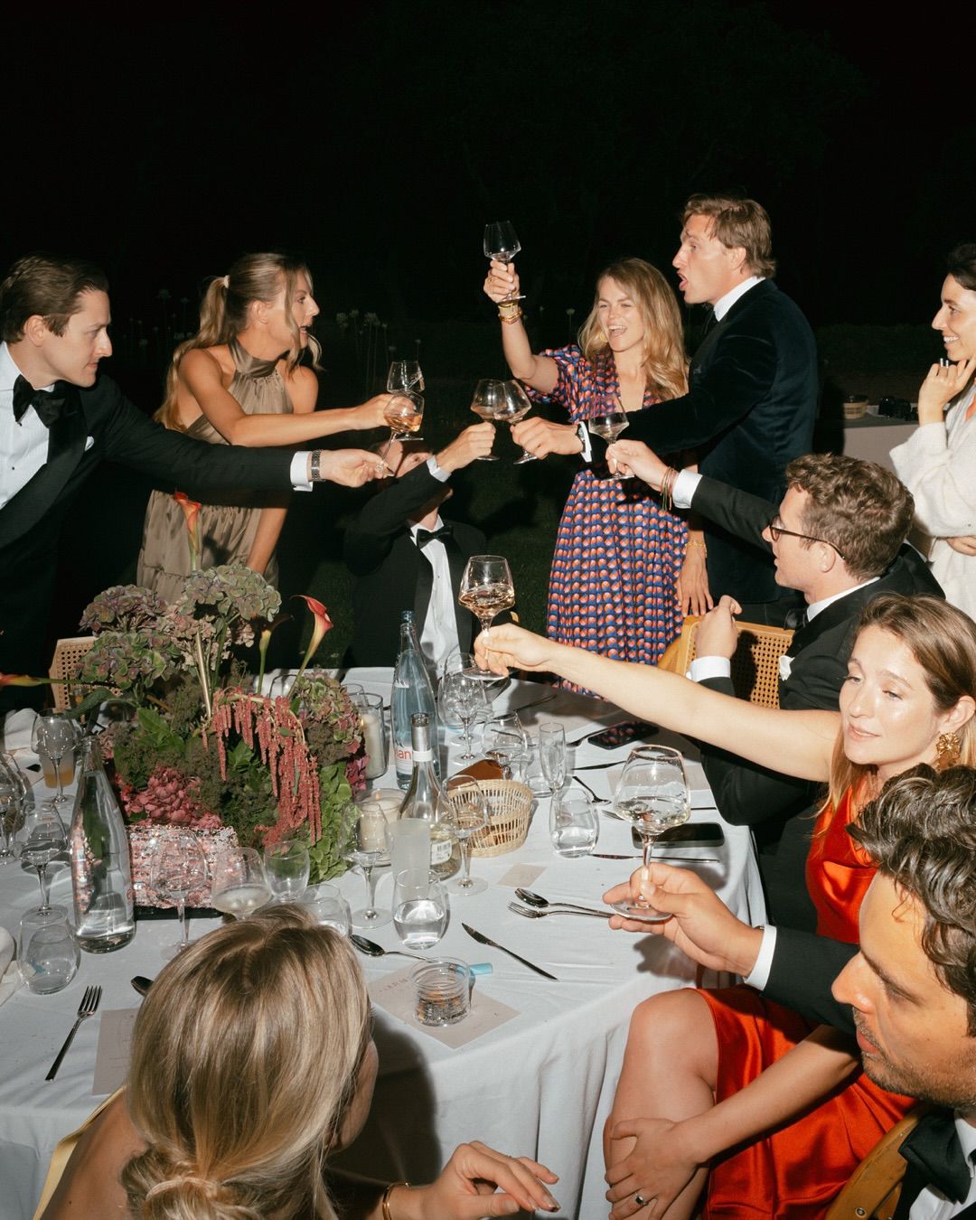 Wedding guests toasting around a table filled with flowers