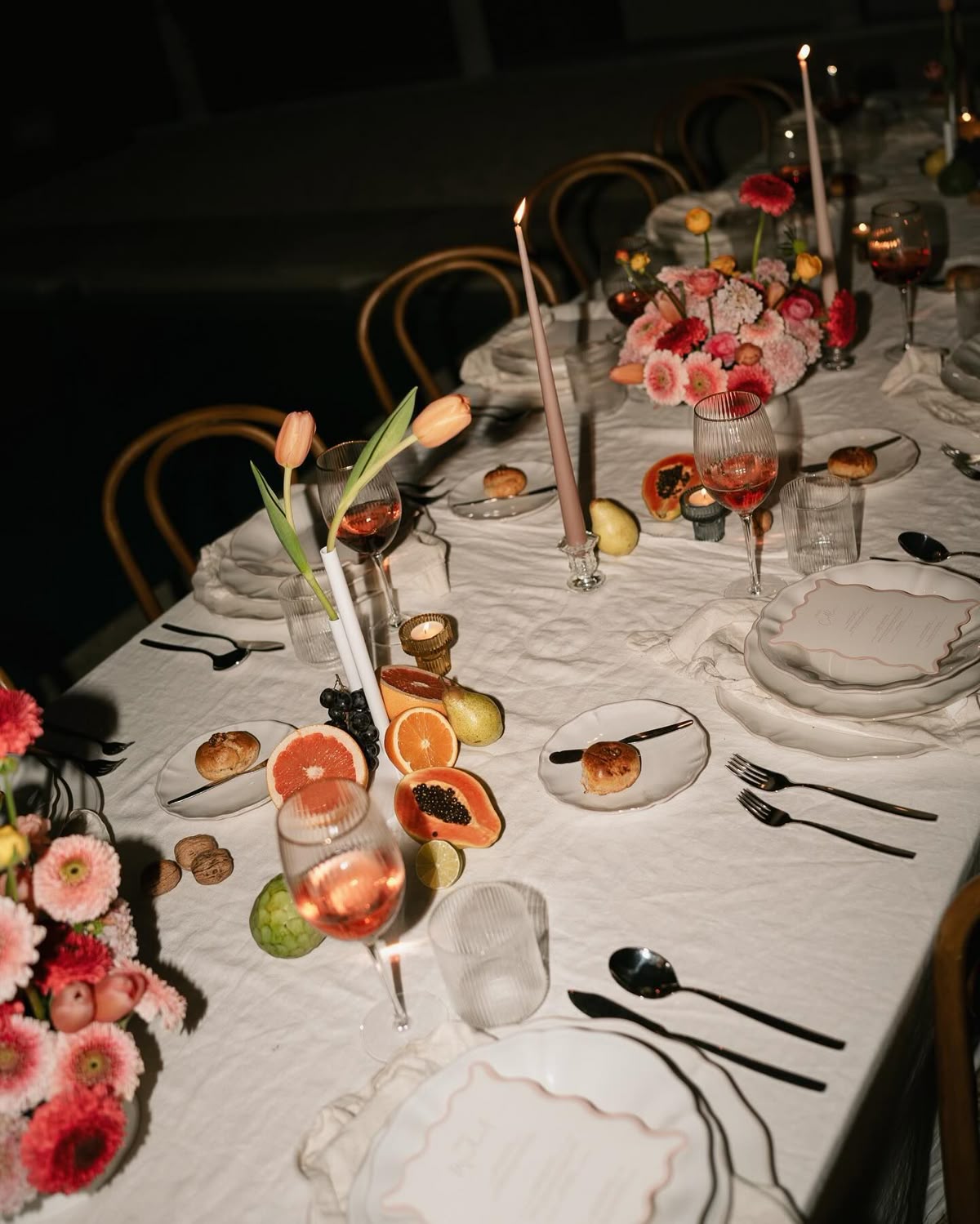 Wedding table with pink flowers, candles and sliced fruit